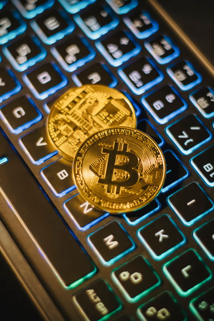digital Two Bitcoin coins resting on an illuminated keyboard, showing cryptocurrency and digital finance themes.